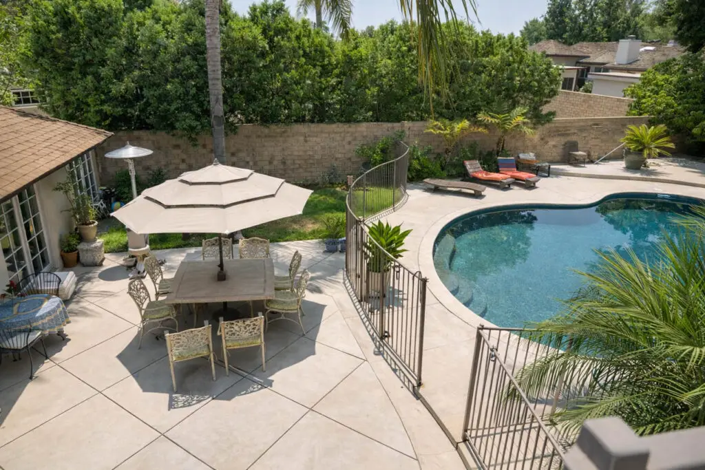 Backyard pool with patio seating and umbrellas at Aura House, Northridge